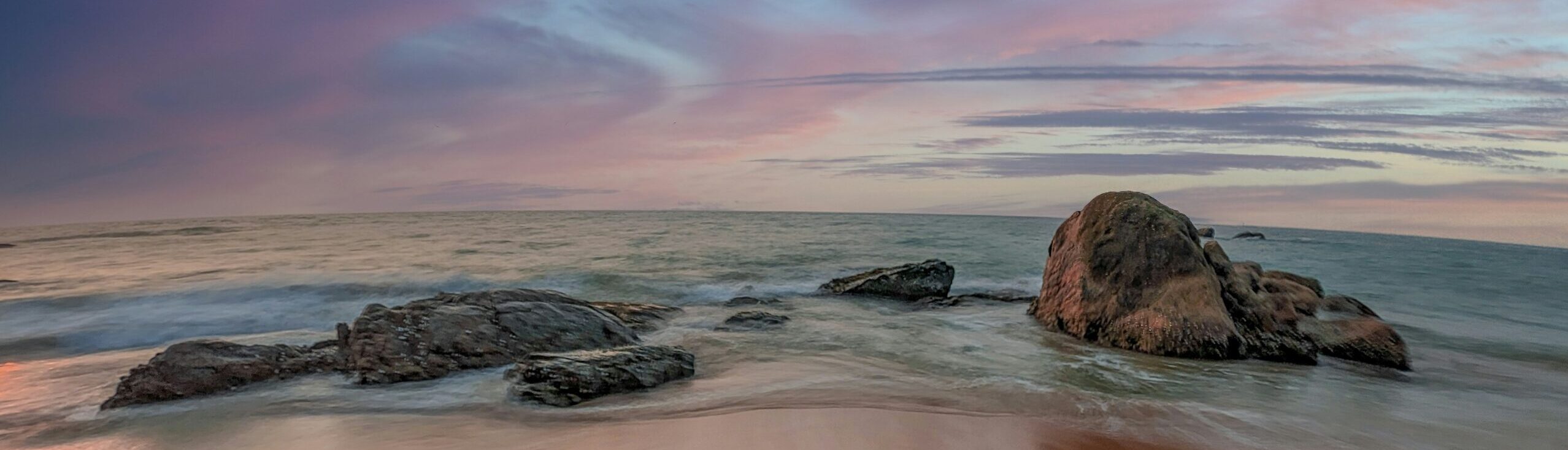 Ocean beach with rocks and colorful sky